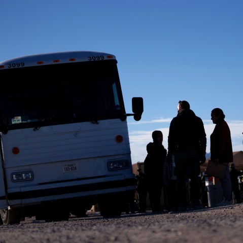 Migrants line up to board a CBP bus for transport