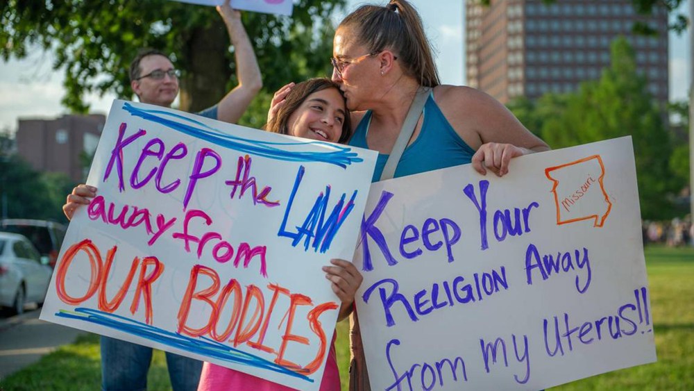 Eleven-year-old Giuliana Cangelosi, left, and her mother Nichole Cangelosi share a moment together while attending a protest opposing the Supreme Court's ruling overturning federal protections for abortion rights June 24, 2022, in Mill Creek Park at Country Club Plaza in Kansas City, Missouri.