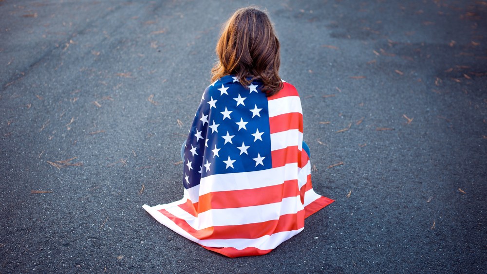 Sad lonely patriot woman sitting down with the american flag