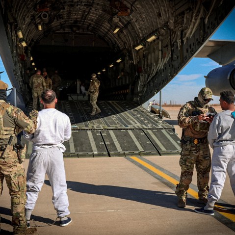 The first U.S. military aircraft to carry detained migrants to Guantanamo Bay is boarded from an unspecified location in the U.S.