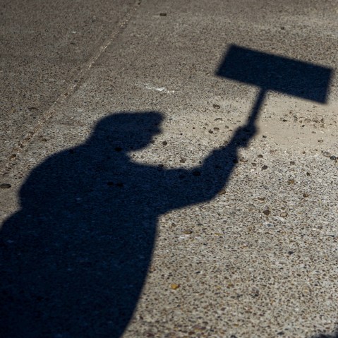 The Shadow Of A Person Holding A Sign.