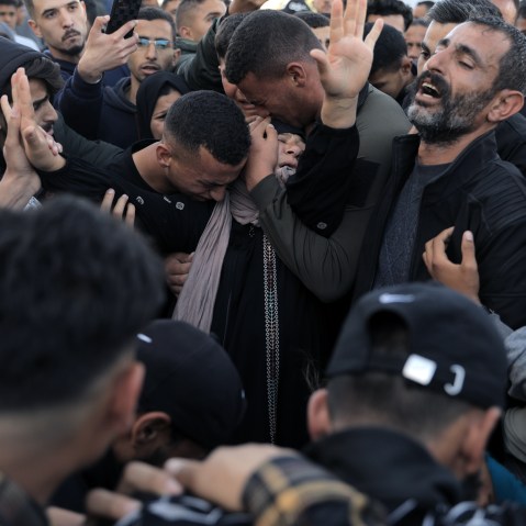 Men crying and hugging a woman at the Hossam Shabbat's funeral
