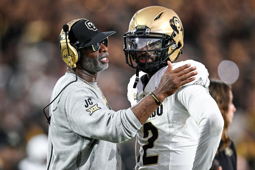 Deion Sanders, left, speaks to Shedeur Sanders on the football field