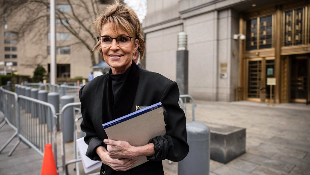 Sarah Palin walks outside holding a notepad