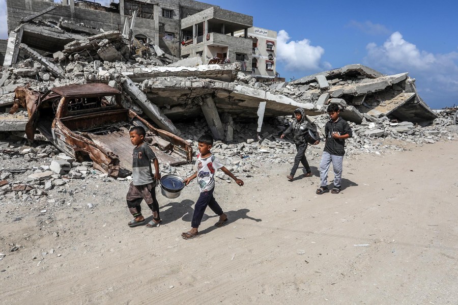 Young Palestinians pass destroyed buildings in Khan Yunis, Gaza, on May 5, 2025. 