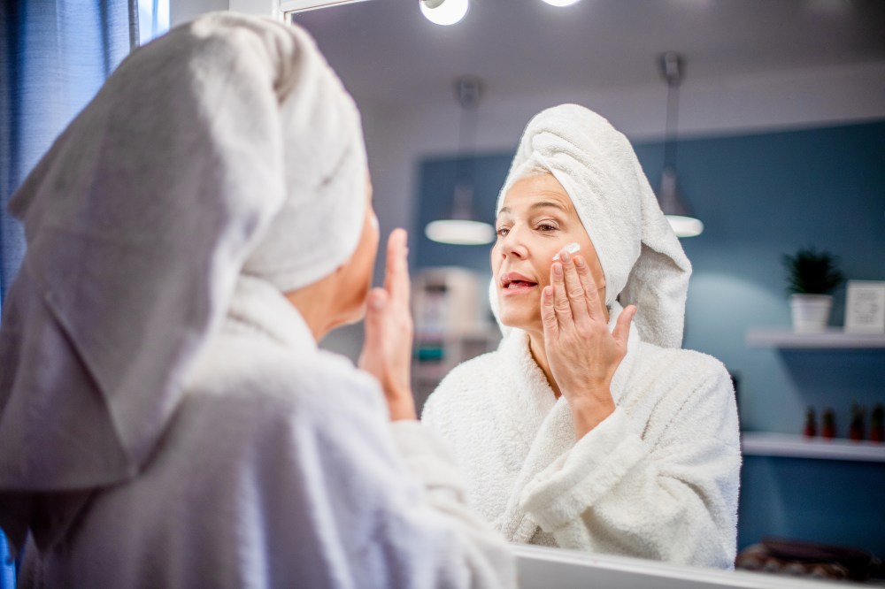 Mature woman applying face cream.