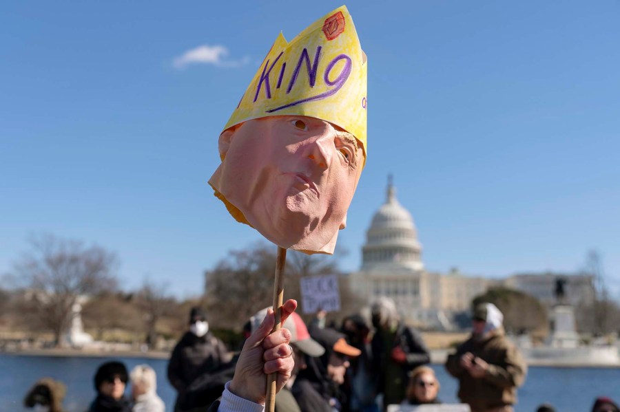A protester holds up a Trump mask at the Presidents Day 