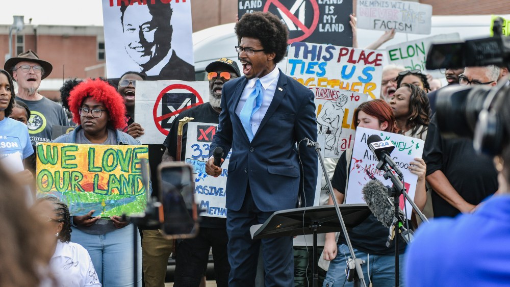 Justin Pearson speaks in the middle of a crowd holding signs against Elon Musk's xAI facility