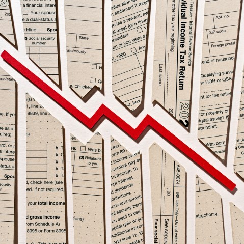 Photo Illustration: a downward trending arrow set against tax return forms