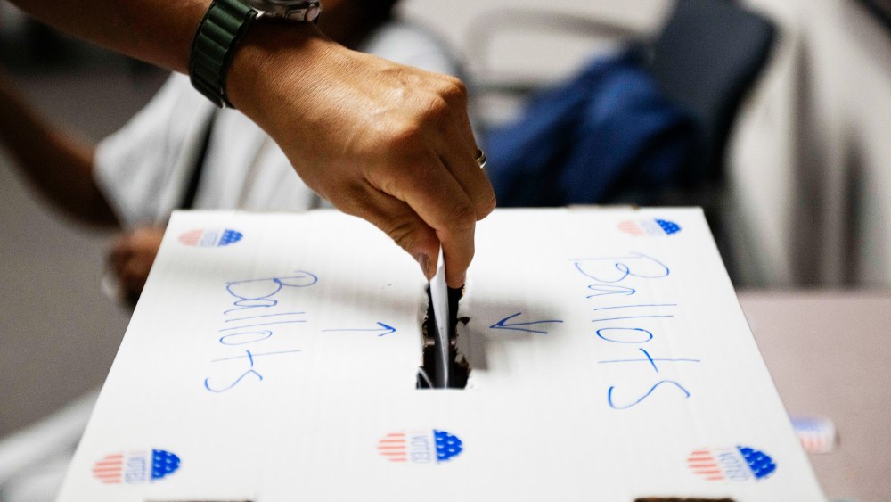 A voter casts a ballot in a box