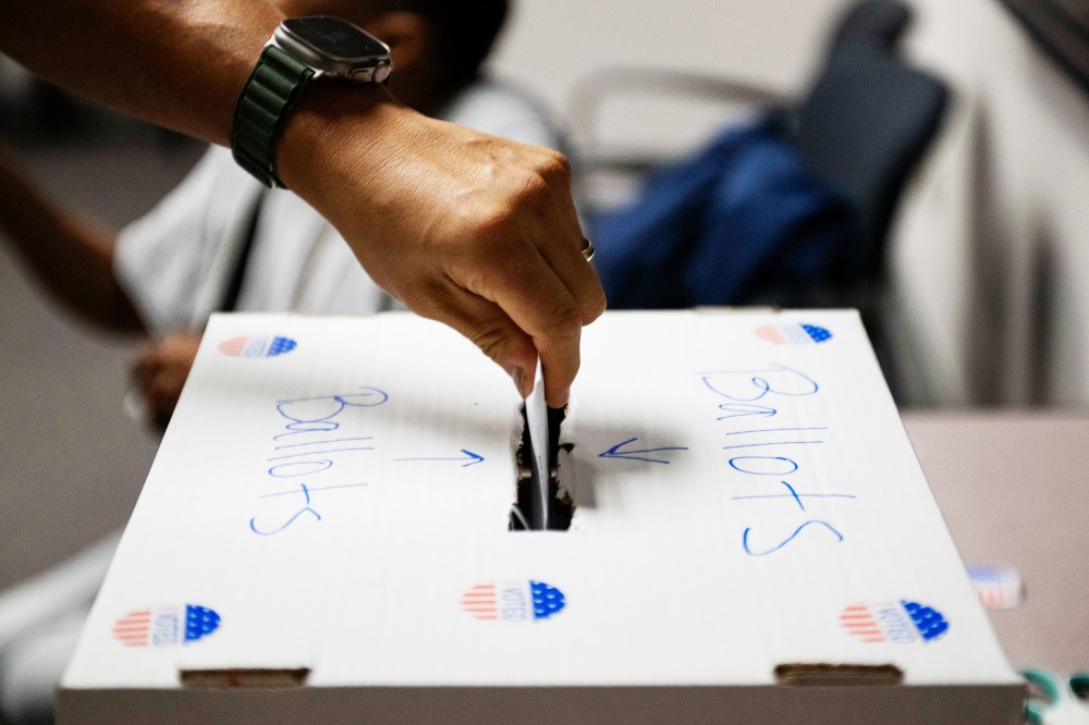 A voter casts a ballot in a box