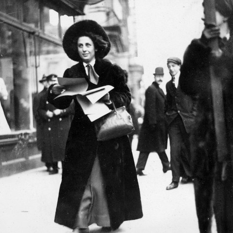 Miss Martha Gruening distributes literature publicizing the Women's Suffrage Movement to passers-by outside the Lyceum Theatre, circa 1912.