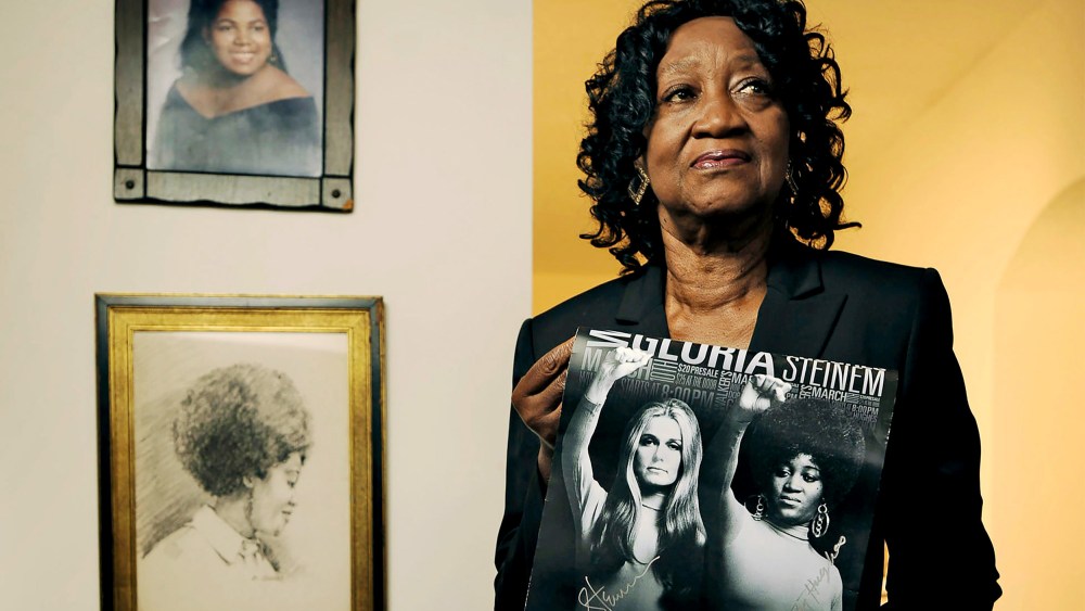 Dorothy Pitman Hughes poses in her St. Johns, Fla. home on Sept.  24, 2013, holding a poster using a 1970's image of herself and Gloria Steinem.