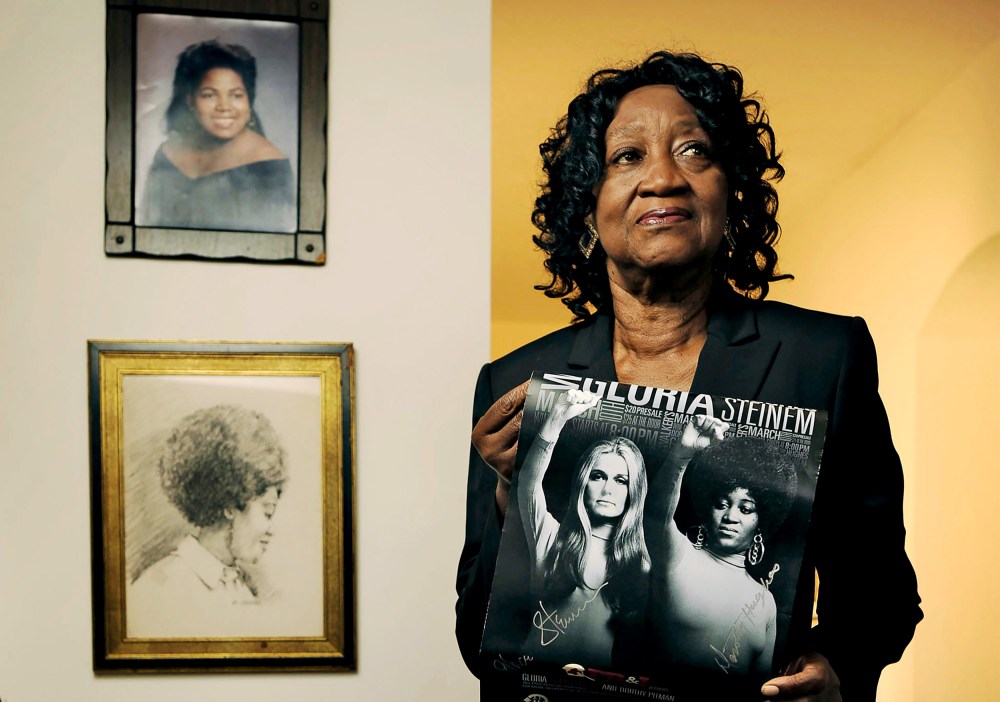 Dorothy Pitman Hughes poses in her St. Johns, Fla. home on Sept.  24, 2013, holding a poster using a 1970's image of herself and Gloria Steinem.