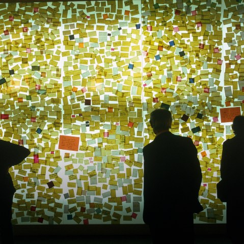 Curious visitors read sticky notes on a wall. (Photo by Construction Photography/Corbis)