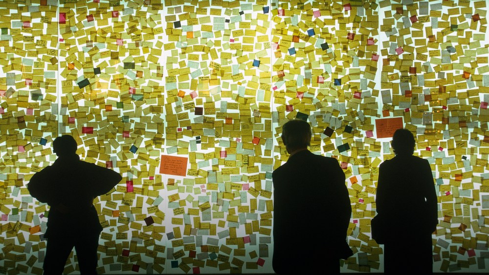 Curious visitors read sticky notes on a wall. (Photo by Construction Photography/Corbis)