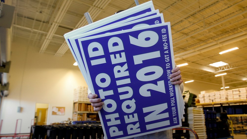 A worker carries signs about a voter ID law that went into effect in 2016 at the Mecklenburg County Board of Elections warehouse in Charlotte, N.C., Nov. 3, 2014. (Photo by Chris Keane/Reuters/Corbis)