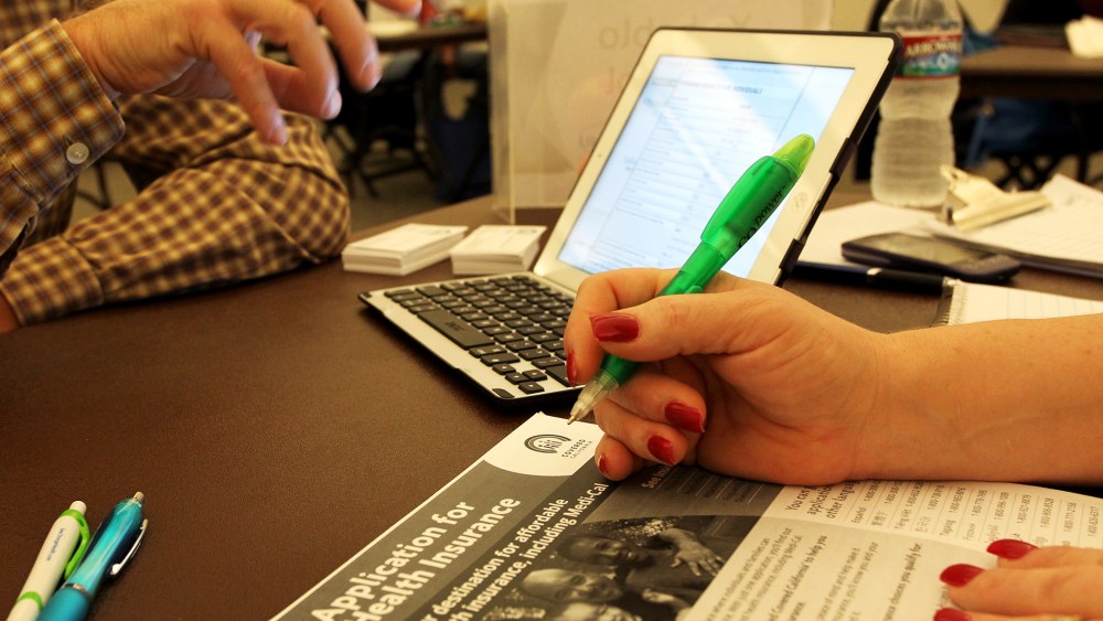 A healthcare reform specialist helps people select insurance plans at an ACA Enrollment Fair in Pasadena, Calif. Nov. 19, 2013.
