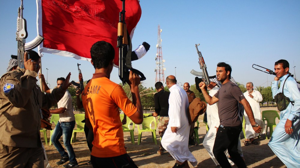 Iraqi Shiite fighters round dance raising up their weapons as they show their willingness to join Iraqi security forces in the fight against Jihadist militants on June 23, 2014 during a gathering in the southern city of Basra.