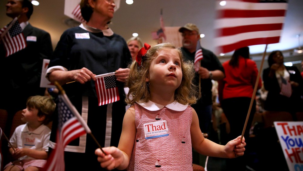 A young supporter of U.S. Sen Thad Cochran (R-MS) waves American flags during a campaign rally on June 23, 2014 in Jackson, Mississippi.