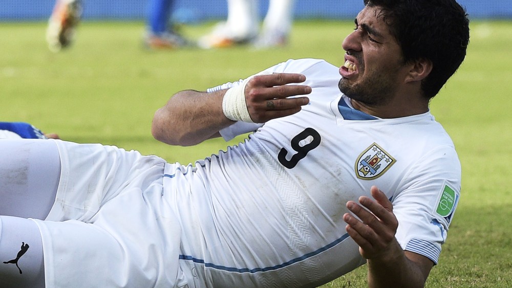 Uruguay forward Luis Suarez puts his hand to his mouth after clashing with Italy's defender Giorgio Chiellini, June 24, 2014.