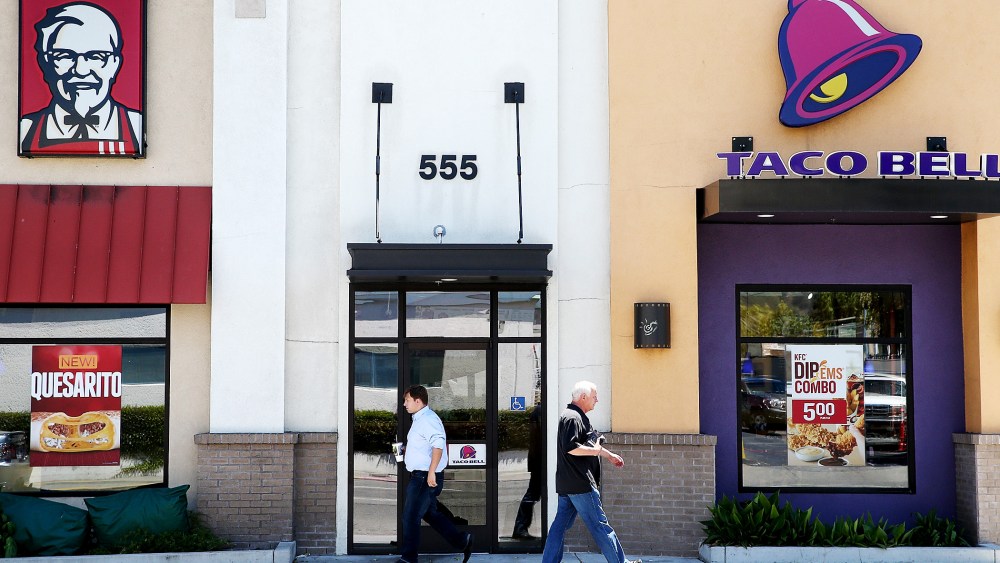 Pedestrians walk by a KFC and a Taco Bell restaurant on July 2, 2014 in San Rafael, California.
