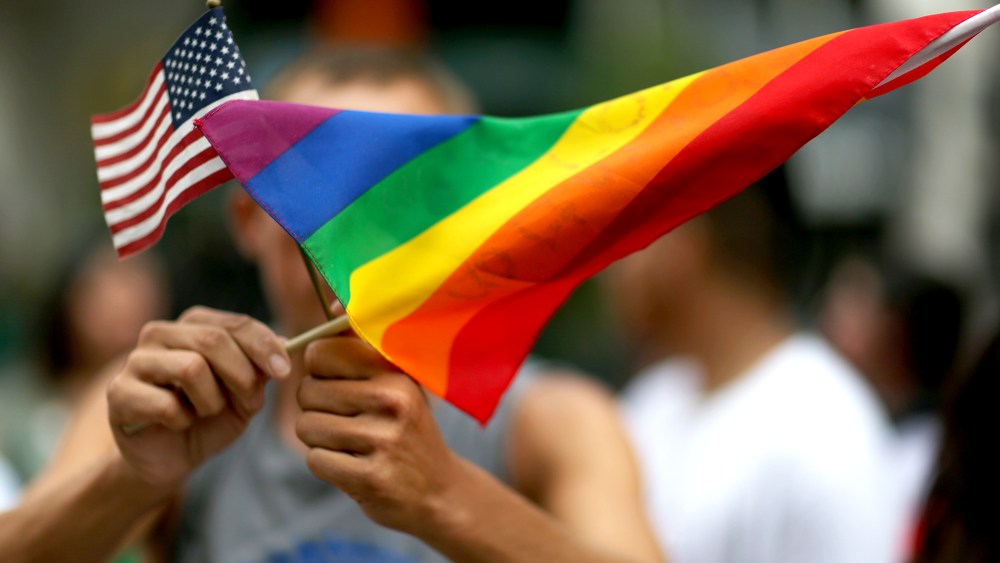 A protester holds an American flag and rainbow flag.