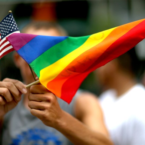 A protester holds an American flag and a rainbow flag.