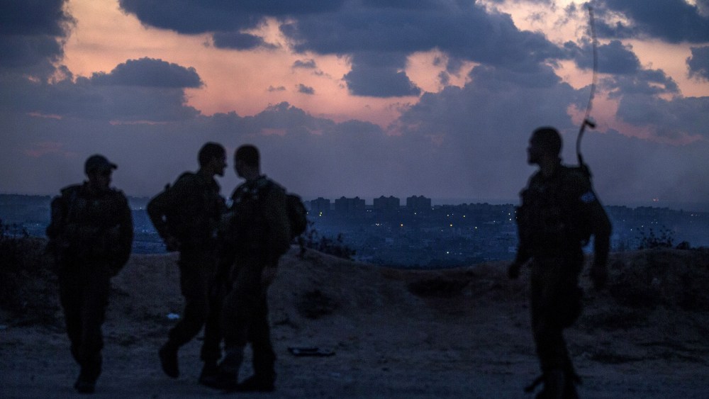 Israeli soldiers stand near the southern Israeli border with the Gaza Strip (background) on July 17, 2014.
