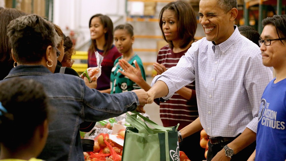 President Barack Obama, first lady Michelle Obama, and their daughters Sasha Obama, 12, and Malia Obama, 15, help pack and distribute bags of food to needy children and seniors at the Capital Area Food Bank November 27, 2013 in Washington, DC.