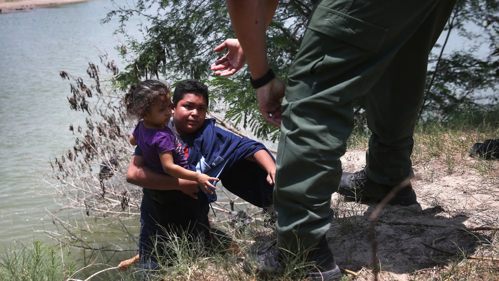 A U.S. Border Patrol agent assists undocumented minors after they crossed the Rio Grande from Mexico into the United States on July 24, 2014 in Mission, Texas.