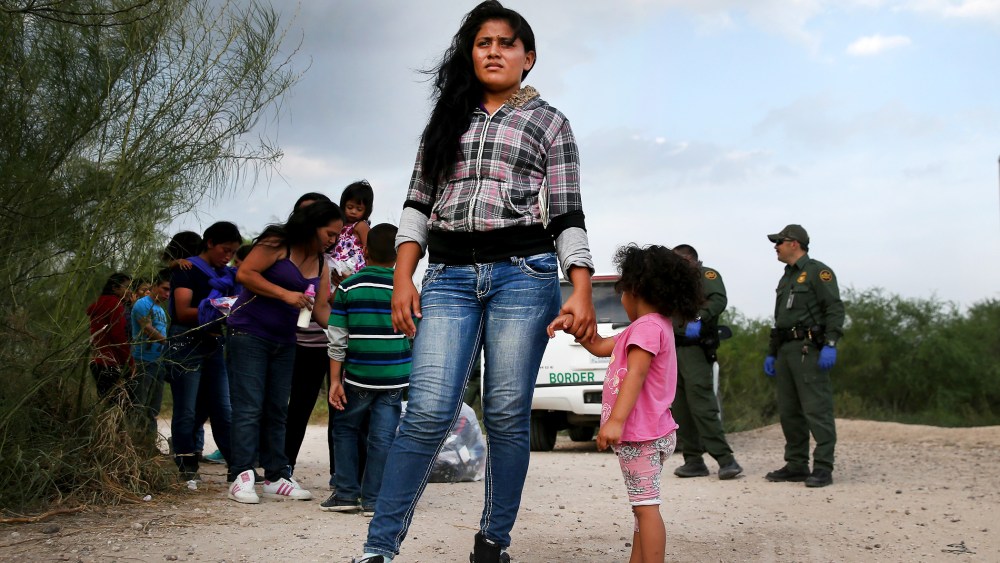 Honduran immigrants wait as a Border Patrol vehicle arrives to transport their group to a processing center, July 24, 2014 in Mission, Texas.