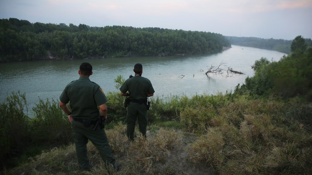 U.S. Border Patrol agents look for immigrants crossing the Rio Grande from Mexico (L), to the United States at dusk on July 24, 2014 near Mission, Texas.