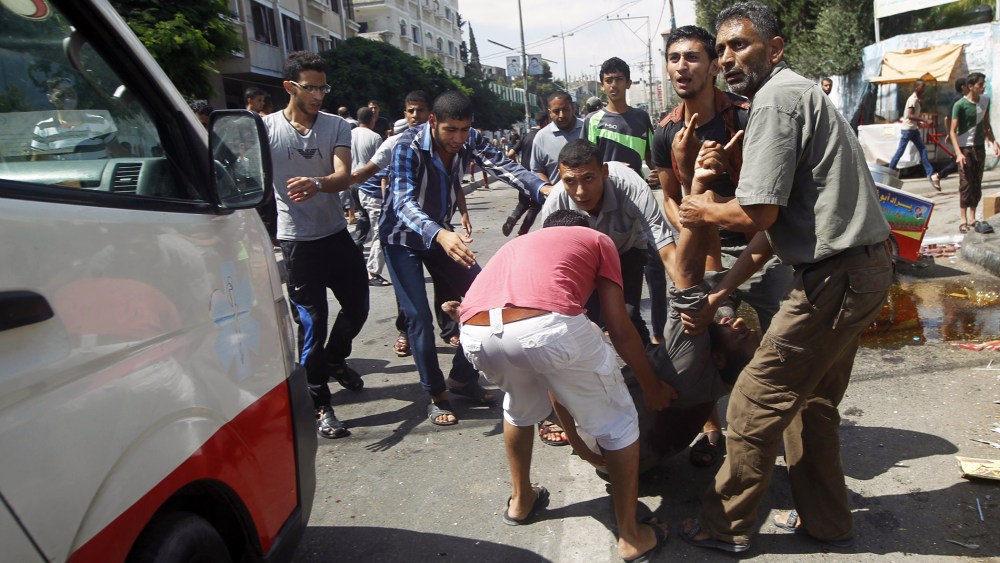 Palestinians carry an injured man following an Israeli military strike on a UN school in Rafah, in the southern Gaza Strip on Aug. 3, 2014.