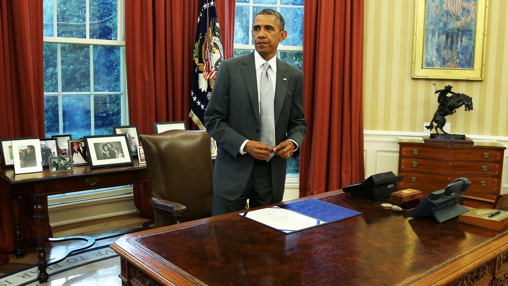 U.S. President Barack Obama stands at his desk in the Oval Office, August 4, 2014.