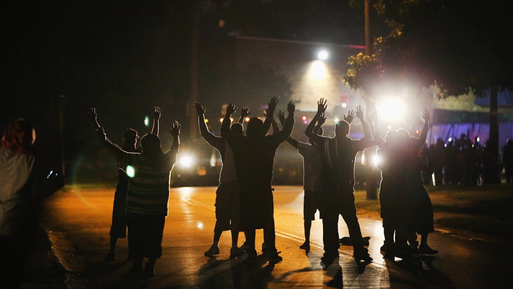 With their hands raised, residents gather in protest at a police line in Ferguson, Mo. on Aug. 11, 2014.