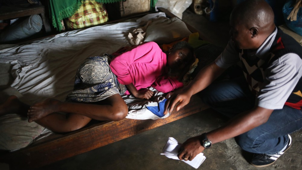 Community organizer John Saah Mbayoh speaks to a sick woman in her one-room home before she is taken to an Ebola isolation ward on August 15, 2014 in Monrovia, Liberia.