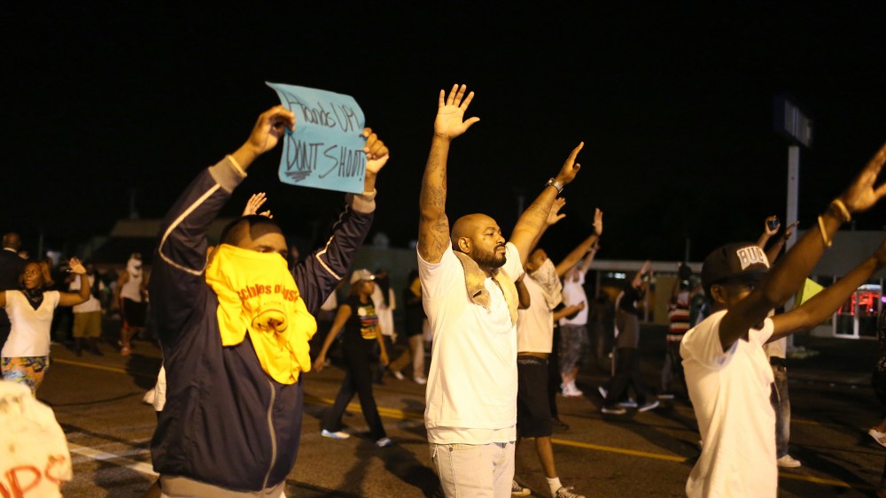Demonstrators raise their arms and chant, "Hands up, Don't Shoot", as police clear them from the street as they protest the shooting death of Michael Brown on Aug. 17, 2014 in Ferguson, Mo.