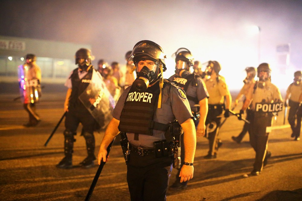 Police advance through a cloud of tear gas toward demonstrators protesting the killing of teenager Michael Brown on August 17, 2014 in Ferguson, Missouri.