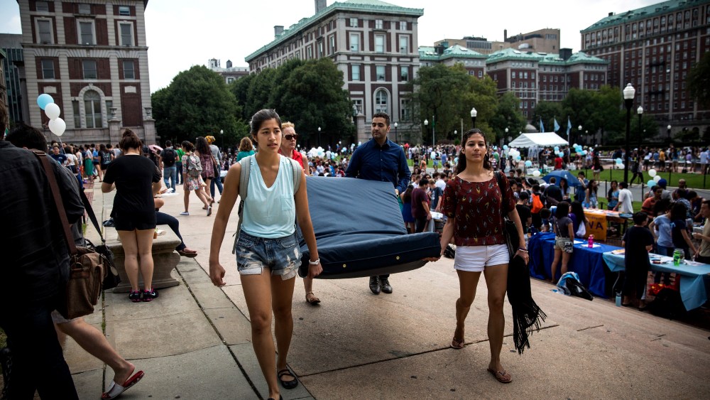 Emma Sulkowicz (L), a then-senior at Columbia University, carries a mattress with the help of three strangers, protesting the university's lack of action after she reported being raped, on Sept. 5, 2014 in New York City. (Photo by Andrew Burton/Getty)