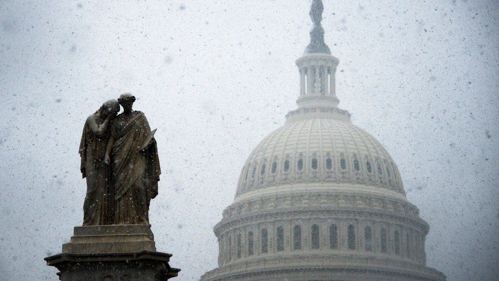 Snow begins to gather on a statue outside the Capitol Building in Washington, DC, Dec. 10, 2013.
