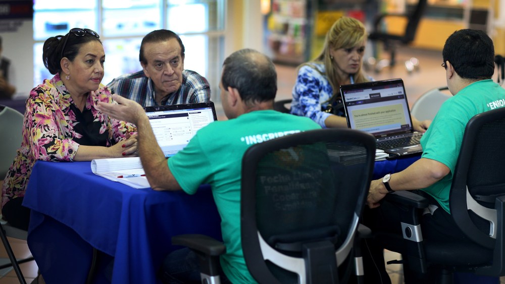 Marlene Gonzalez (L) and Alberto Gonzalez (2nd L) speak with Jose Luis Gonzalez (C), an insurance agent with Sunshine Life and Health Advisors, about purchasing insurance under the Affordable Care Act at a kiosk setup at the Mall of Americas on December 1