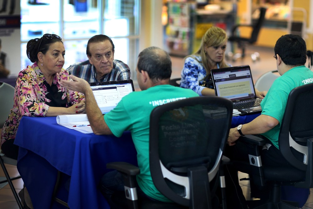 Marlene Gonzalez (L) and Alberto Gonzalez (2nd L) speak with Jose Luis Gonzalez (C), an insurance agent with Sunshine Life and Health Advisors, about purchasing insurance under the Affordable Care Act at a kiosk setup at the Mall of Americas on December 1