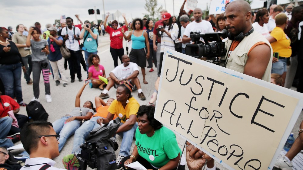 Demonstrators sit in the street after police prevented them from gaining access to Interstate Highway 70 during a protest on Sept. 10, 2014 near Ferguson, Mo.