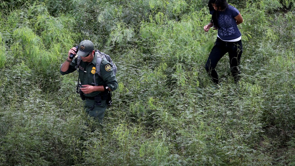 A U.S. Border Patrol escorts an undocumented immigrant, her arm handcuffed behind her back, after detaining her in the brush on Sept. 11, 2014 near Falfurrias, Texas.