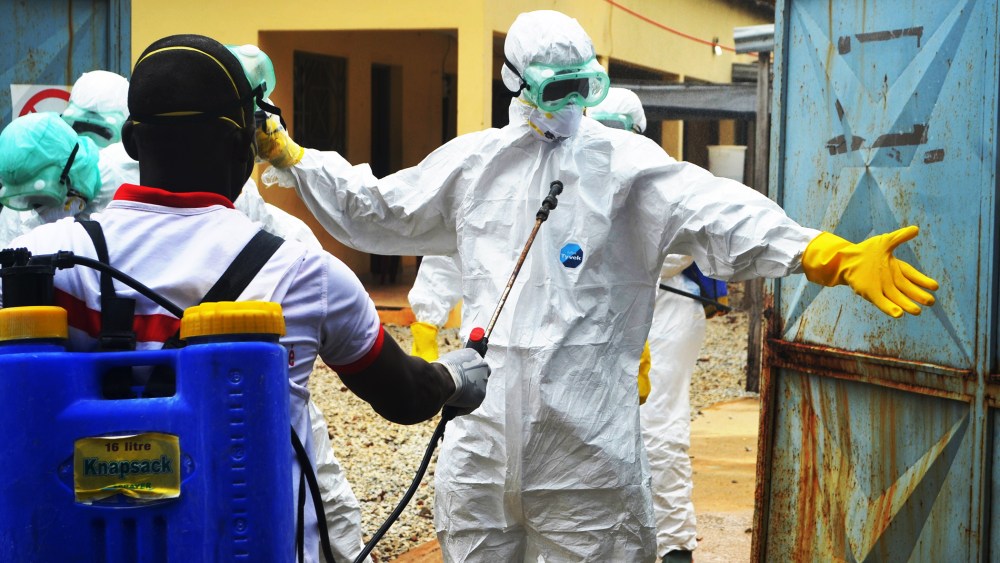 Guinea's Red Cross health workers wear protective suits prepare to carry the body of a victim of Ebola near the hospital Donka in Conakry, Sept. 14, 2014.