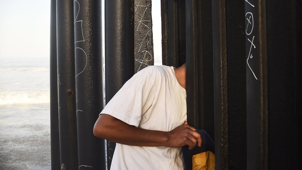 A man looks through the fence that divides Mexico and the US, in Tijuana, Baja California State, Mexico, on September 17, 2014.