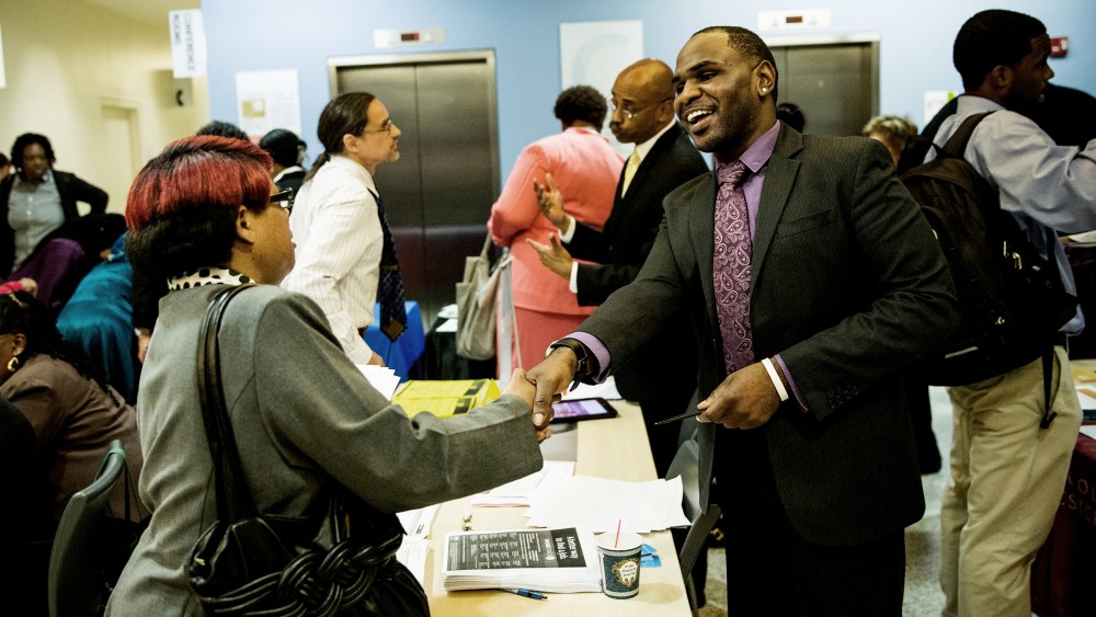Carl Gilbert (R), of Upper Manhattan Work Force 1 Career Center, meets with a woman looking for a job at a jobs fair at the Bronx Public Library on Sept. 17, 2014 in the Bronx Borough of New York, N.Y. (Photo by Andrew Burton/Getty)