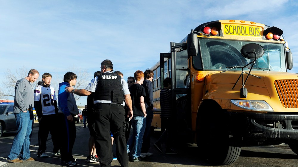 A Douglas County Sheriff's Deputy helps students to board a bus after a school shooting on December 13, 2013 at Arapahoe High School in Centennial, Colorado.