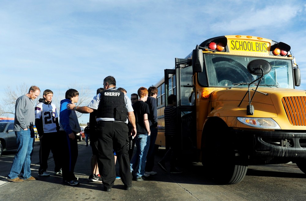 A Douglas County Sheriff's Deputy helps students to board a bus after a school shooting on December 13, 2013 at Arapahoe High School in Centennial, Colorado.